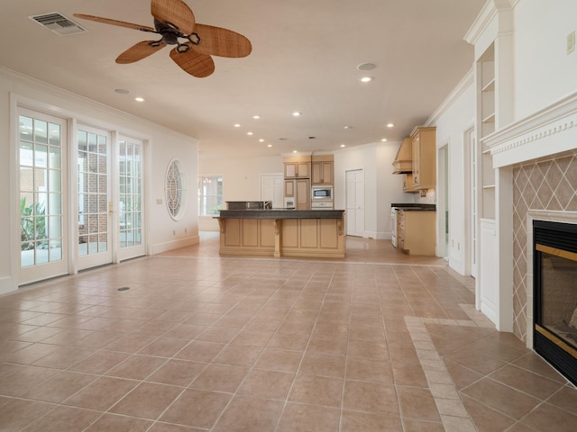 unfurnished living room featuring a fireplace, ceiling fan, crown molding, and light tile patterned flooring