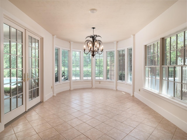 unfurnished sunroom featuring a notable chandelier, plenty of natural light, and french doors