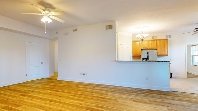 interior space featuring ceiling fan with notable chandelier and light hardwood / wood-style flooring