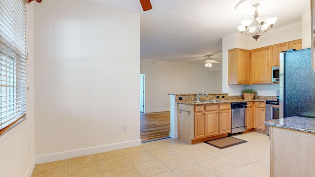 kitchen featuring sink, appliances with stainless steel finishes, hanging light fixtures, ceiling fan with notable chandelier, and kitchen peninsula