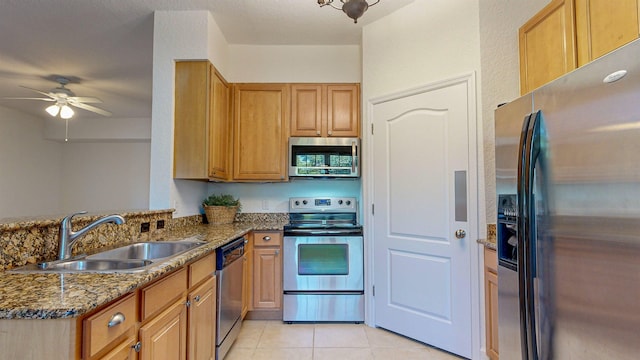 kitchen with sink, light tile patterned floors, stainless steel appliances, kitchen peninsula, and dark stone counters