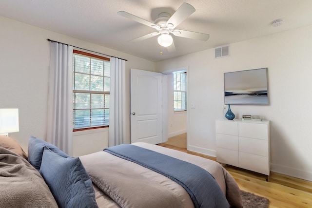 bedroom with ceiling fan, multiple windows, and light wood-type flooring