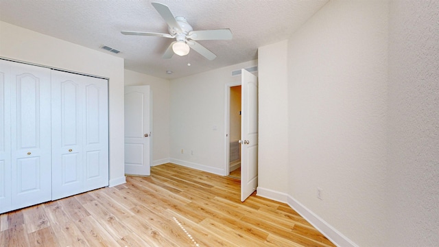 unfurnished bedroom featuring ceiling fan, light hardwood / wood-style flooring, a closet, and a textured ceiling