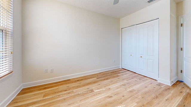 unfurnished bedroom with ceiling fan, a textured ceiling, light wood-type flooring, and a closet