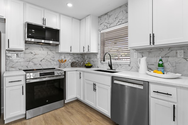 kitchen featuring white cabinets, appliances with stainless steel finishes, decorative backsplash, and sink