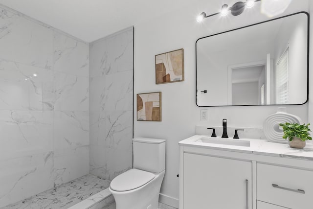 bathroom with tiled shower, vanity, and toilet