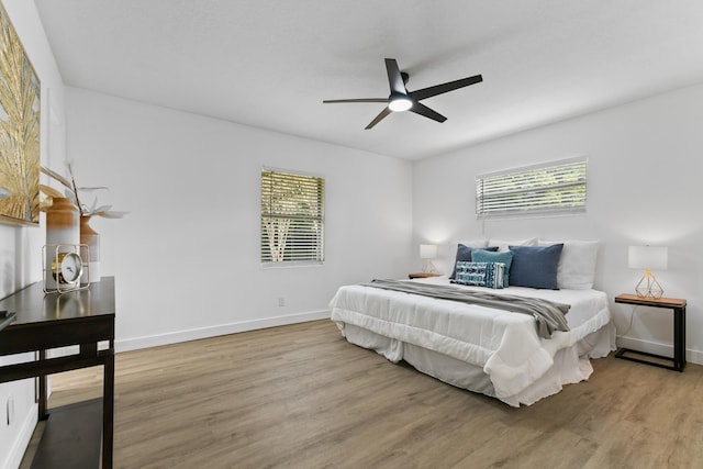 bedroom with ceiling fan, wood-type flooring, and multiple windows