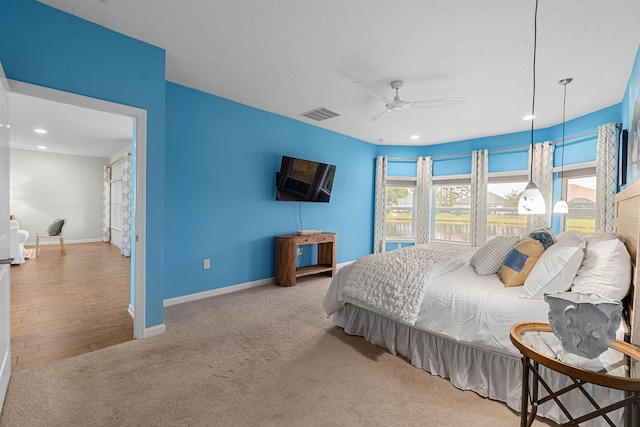 carpeted bedroom featuring baseboards, visible vents, a textured ceiling, and recessed lighting