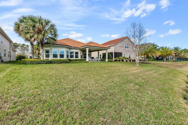 back of property featuring a tiled roof and a yard