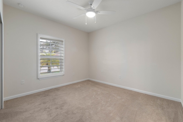 empty room featuring baseboards, a ceiling fan, and light colored carpet