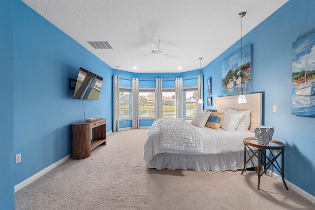 bedroom featuring a textured ceiling, carpet flooring, a ceiling fan, visible vents, and baseboards