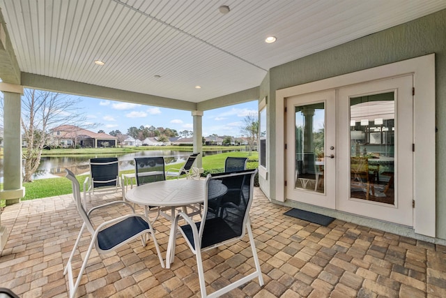 view of patio / terrace with a water view, french doors, and outdoor dining space