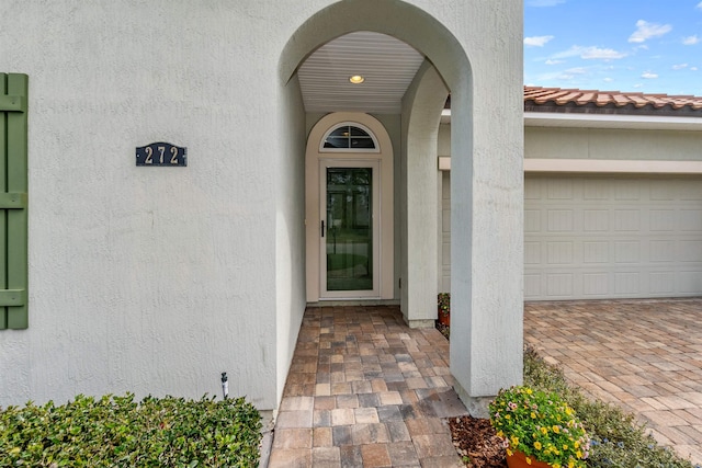 property entrance featuring an attached garage, a tiled roof, and stucco siding