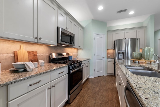 kitchen with dark wood-style floors, stainless steel appliances, tasteful backsplash, and a sink