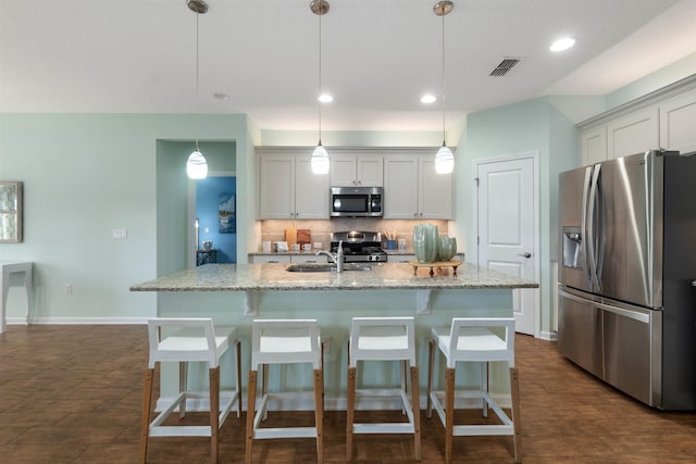 kitchen with a breakfast bar area, a sink, visible vents, appliances with stainless steel finishes, and tasteful backsplash