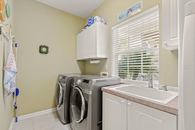 washroom with cabinets, light tile patterned floors, washer and clothes dryer, and sink