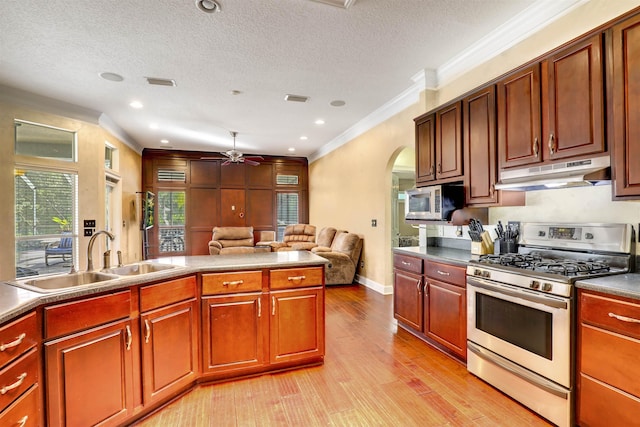 kitchen featuring ceiling fan, sink, stainless steel appliances, light hardwood / wood-style flooring, and a textured ceiling