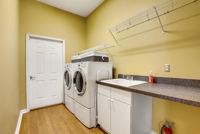 laundry area featuring washing machine and dryer, sink, and light hardwood / wood-style floors