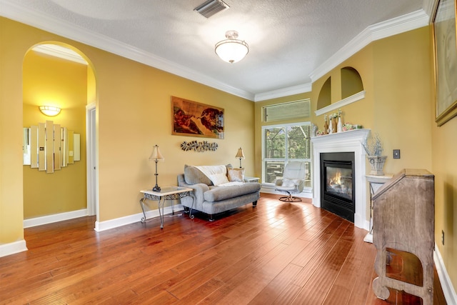 sitting room with wood-type flooring, a textured ceiling, and ornamental molding