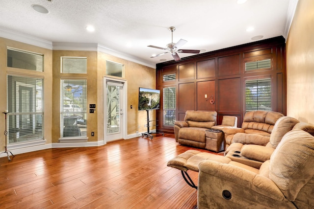 living room with a textured ceiling, light hardwood / wood-style flooring, ceiling fan, and ornamental molding