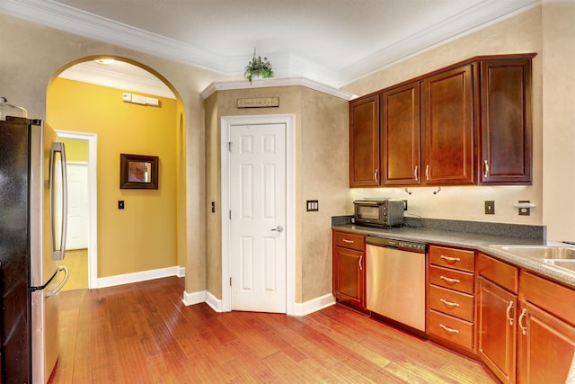 kitchen featuring sink, light hardwood / wood-style flooring, ornamental molding, and appliances with stainless steel finishes