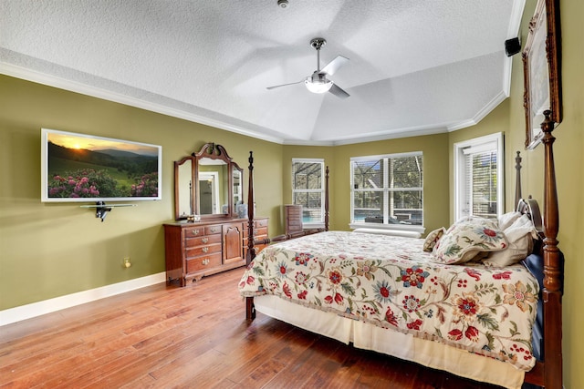 bedroom with crown molding, vaulted ceiling, hardwood / wood-style flooring, ceiling fan, and a textured ceiling