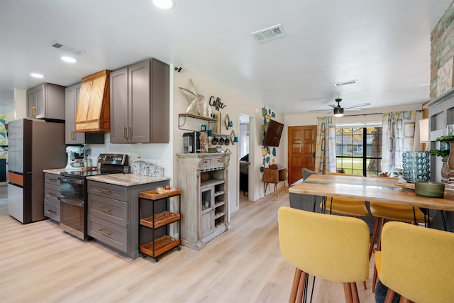 kitchen featuring backsplash, ceiling fan, gray cabinets, appliances with stainless steel finishes, and light hardwood / wood-style floors