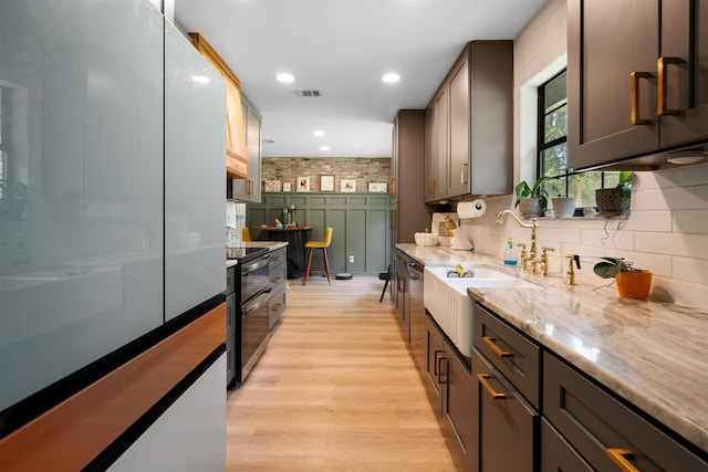 kitchen with sink, stainless steel appliances, tasteful backsplash, light hardwood / wood-style floors, and dark brown cabinets