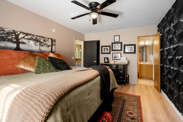 bedroom featuring ensuite bathroom, light hardwood / wood-style flooring, and ceiling fan