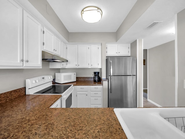 850 A1A Beach Blvd Unit 42, Saint Augustine Beach, FL 32080 - kitchen with white appliances, under cabinet range hood, white cabinets, and dark countertops