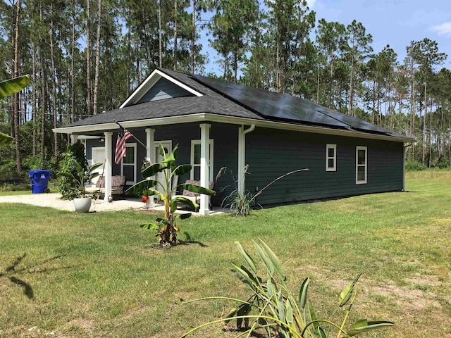 view of property exterior with solar panels and a yard