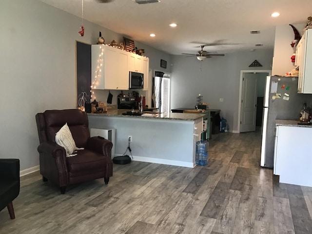 kitchen featuring dark hardwood / wood-style flooring, white cabinetry, kitchen peninsula, and appliances with stainless steel finishes