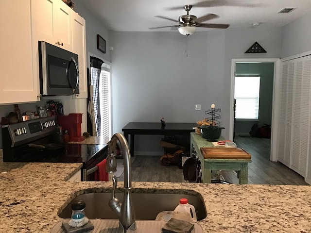 kitchen with sink, white cabinets, dark wood-type flooring, and range