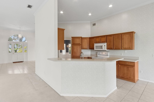 kitchen featuring white microwave, brown cabinetry, range with electric cooktop, light countertops, and visible vents