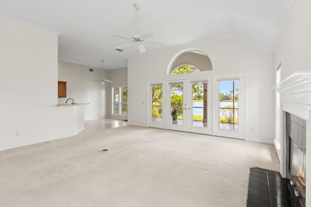 unfurnished living room featuring a tiled fireplace, a ceiling fan, high vaulted ceiling, and light carpet