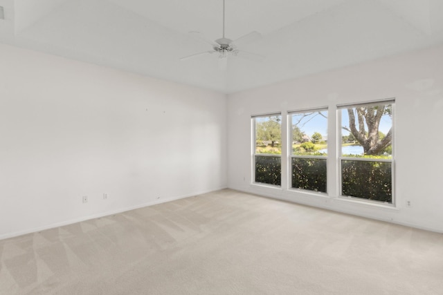 empty room with ceiling fan, baseboards, a water view, and light carpet