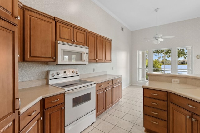 kitchen featuring brown cabinetry, light tile patterned floors, white appliances, and light countertops