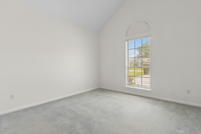 carpeted empty room featuring baseboards and vaulted ceiling