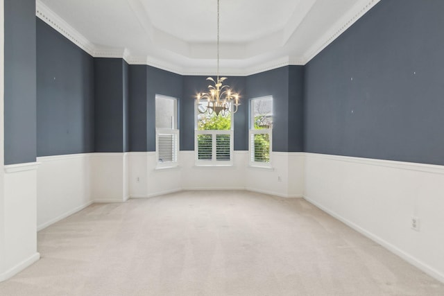 carpeted empty room with a raised ceiling and an inviting chandelier