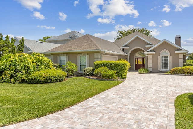 single story home featuring stucco siding, decorative driveway, a front yard, and an attached garage