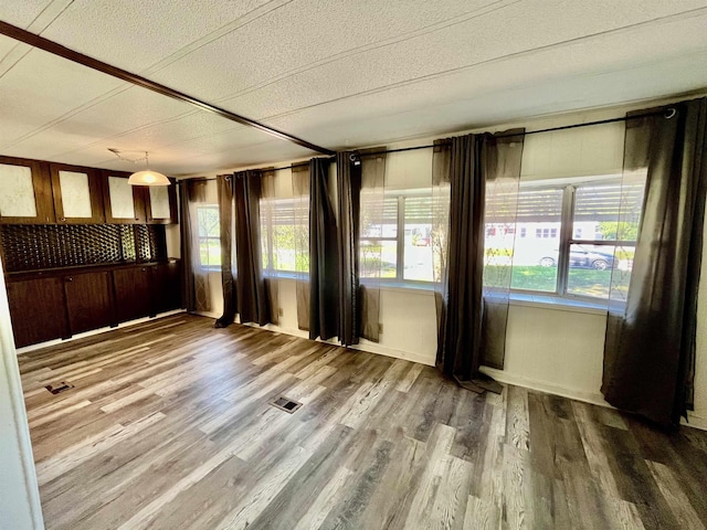 spare room with a wealth of natural light, visible vents, and wood finished floors