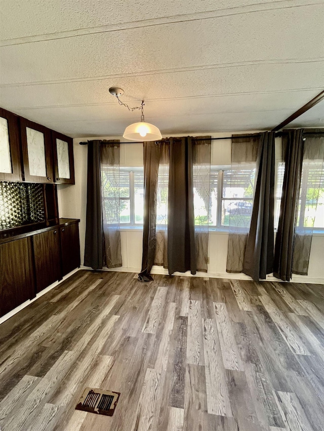 unfurnished dining area featuring wood finished floors and visible vents