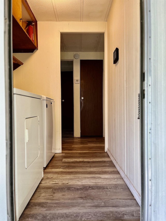 clothes washing area with wood walls, dark wood finished floors, laundry area, and washer and clothes dryer