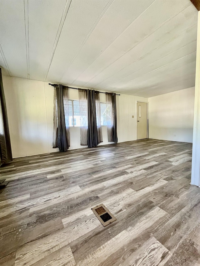 unfurnished room with wood finished floors and visible vents