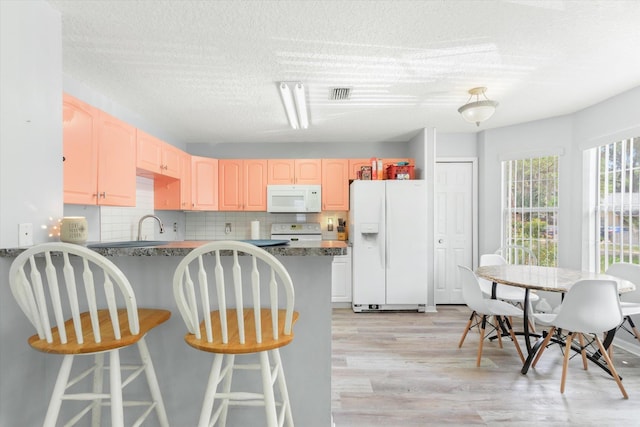 3372 9th St, Elkton, FL 32033 - kitchen with white appliances, a textured ceiling, light wood-style flooring, a peninsula, and visible vents