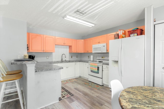3372 9th St, Elkton, FL 32033 - kitchen featuring a sink, light wood finished floors, white appliances, a peninsula, and decorative backsplash