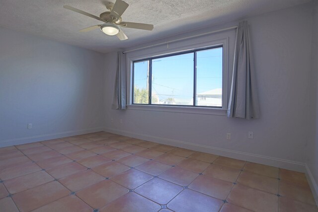 tiled empty room with ceiling fan and a textured ceiling