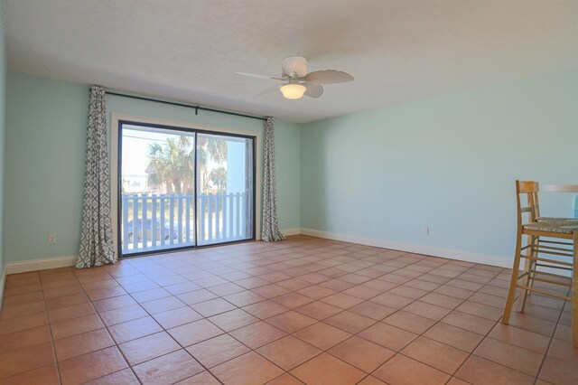 tiled empty room featuring ceiling fan