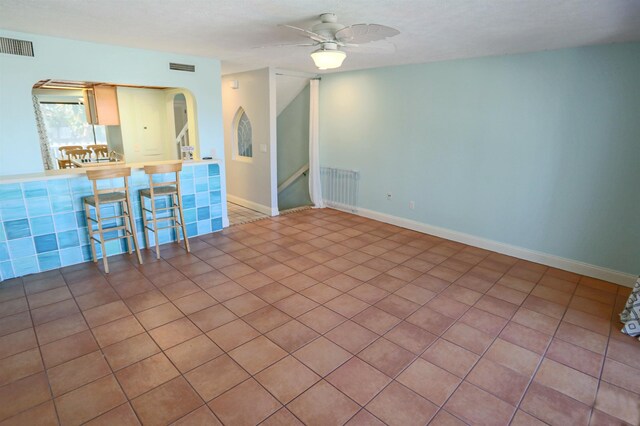 spare room with radiator heating unit, tile patterned floors, and ceiling fan