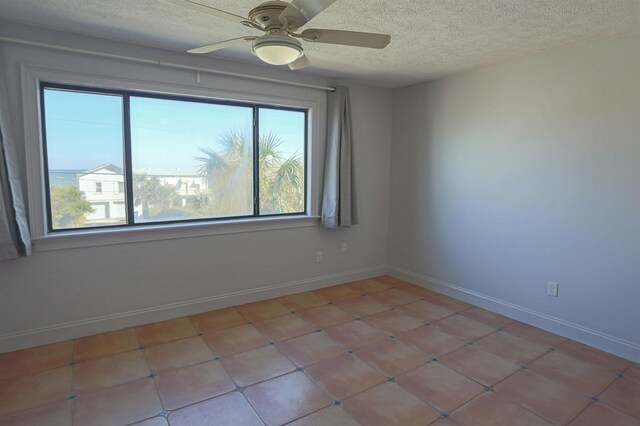 empty room with ceiling fan and a textured ceiling